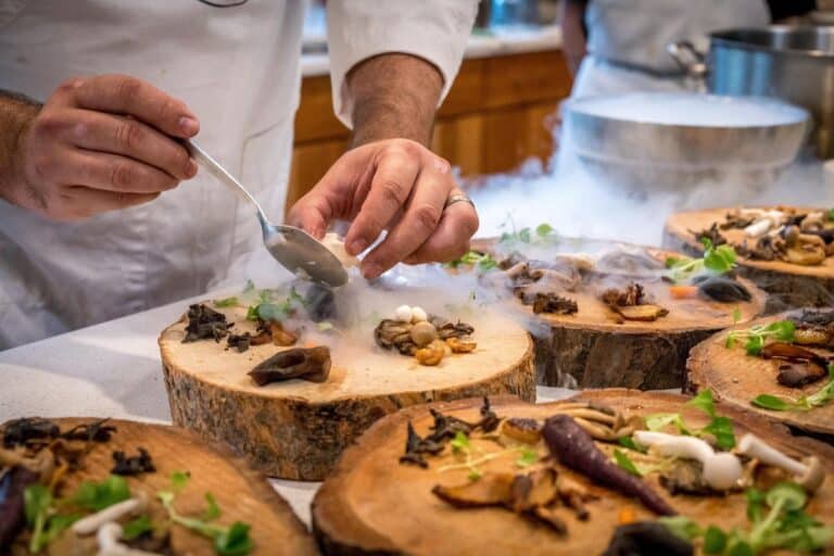 A chef preparing a meal with carrots, green, and mushrooms
