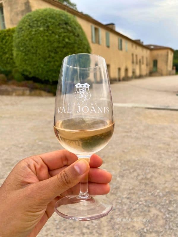 Hand holding a wineglass marked Chateau Val-Joanis, a popular Luberon winery and wedding venue in Provence.