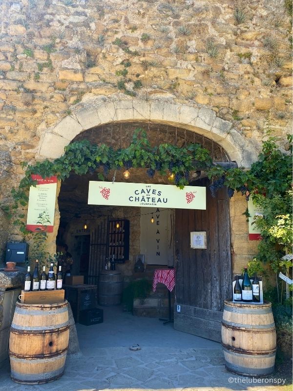 Entrance of Les Caves du Chateau in Lourmarin. There are two big barrels outside with bottles of wines displayed. Go here if you want to taste different wines from the Luberon and France.