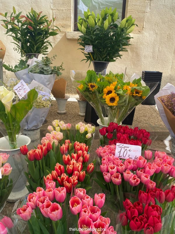 Vibrant bouquets of tulips, sunflowers, and lilies on display for sale at a market in Lourmarin, France.