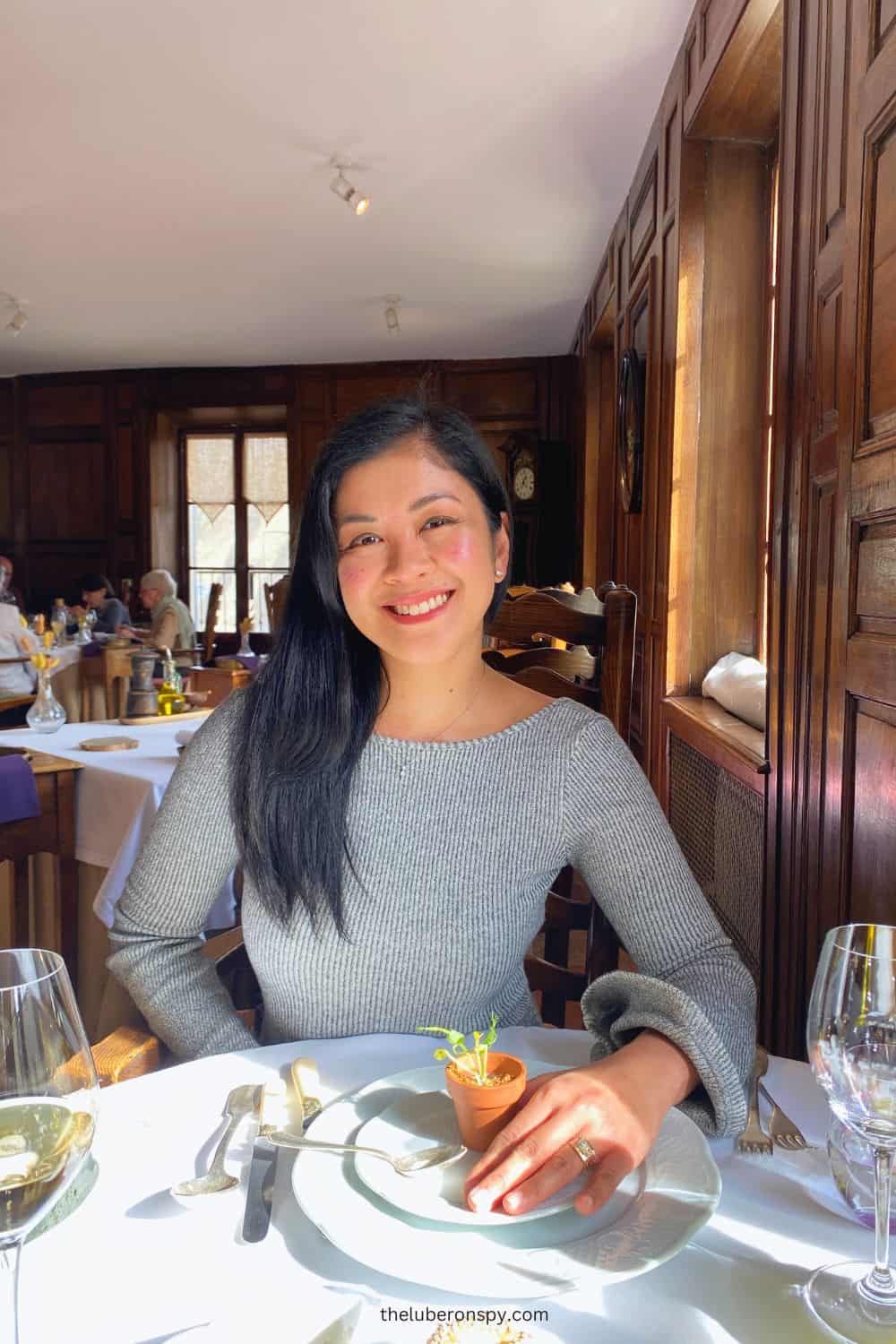 The smiling writer in a Michelin restaurant with elegant table settings and warm wooden decor.