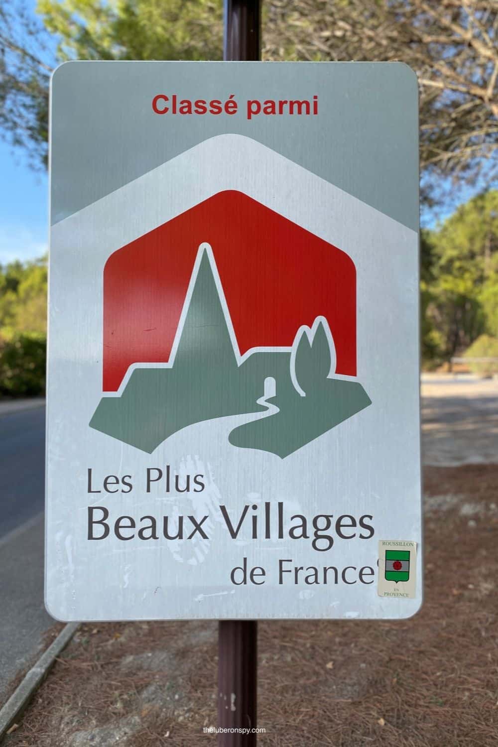 Sign reading 'Classé parmi Les Plus Beaux Villages de France' indicating a village recognized among the most beautiful in France.