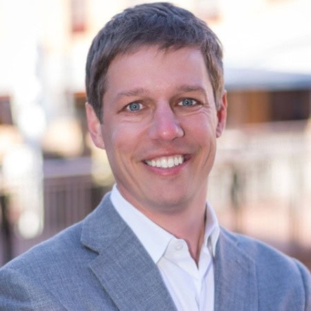Man in gray suit outdoors.