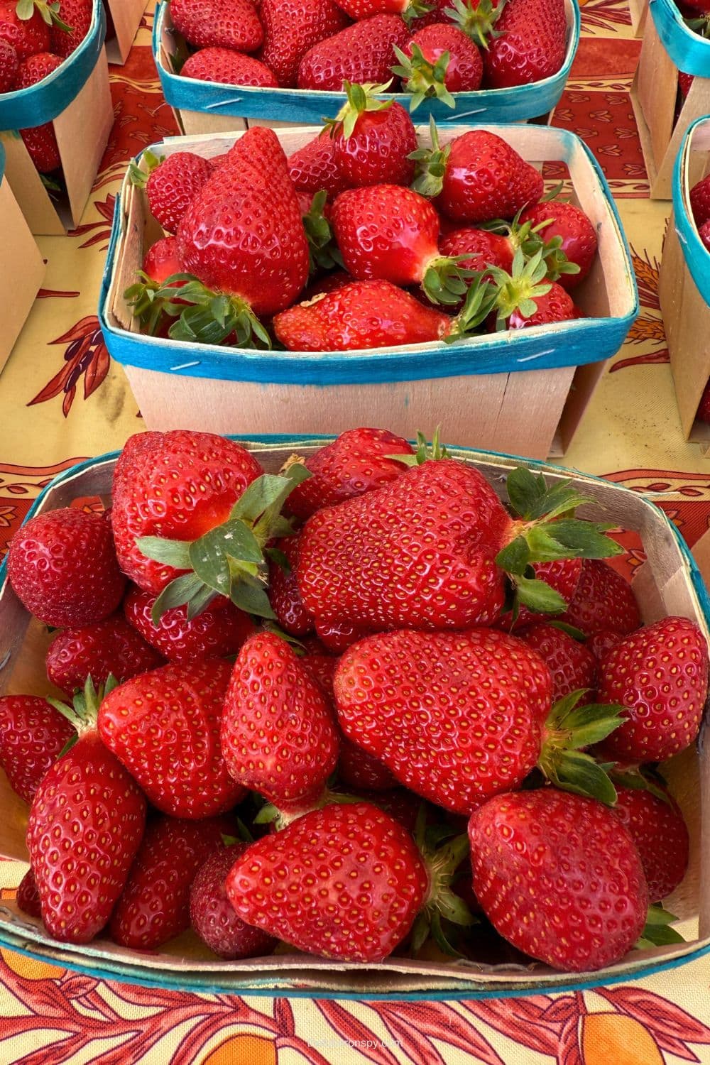 Fresh strawberries piled in blue edged baskets at a Lourmarin market in Provence.