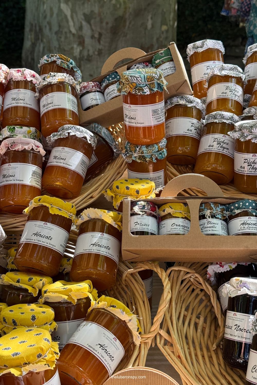 Colorfully packaged jars of Provenรงal fruit preserves including melon peach fig orange quince apricot and sour cherry.