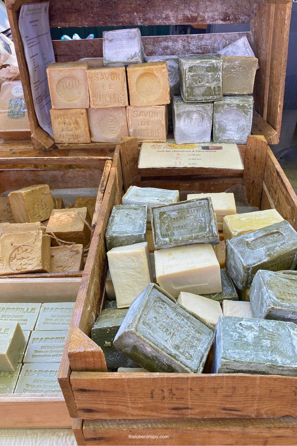 Traditional Marseille soap bars in natural beige and green tones stacked in wooden crates at a market in Luberon, Provence.