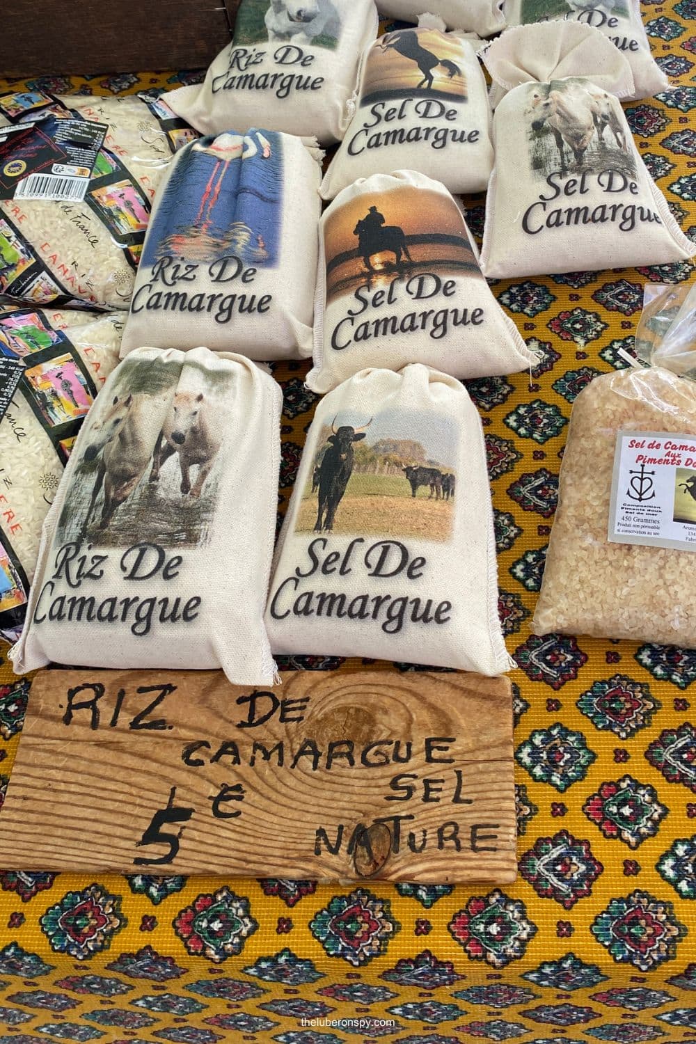 Bags of Camargue rice and natural salt decorated with horses and bulls are displayed at a Lourmarin market stall.